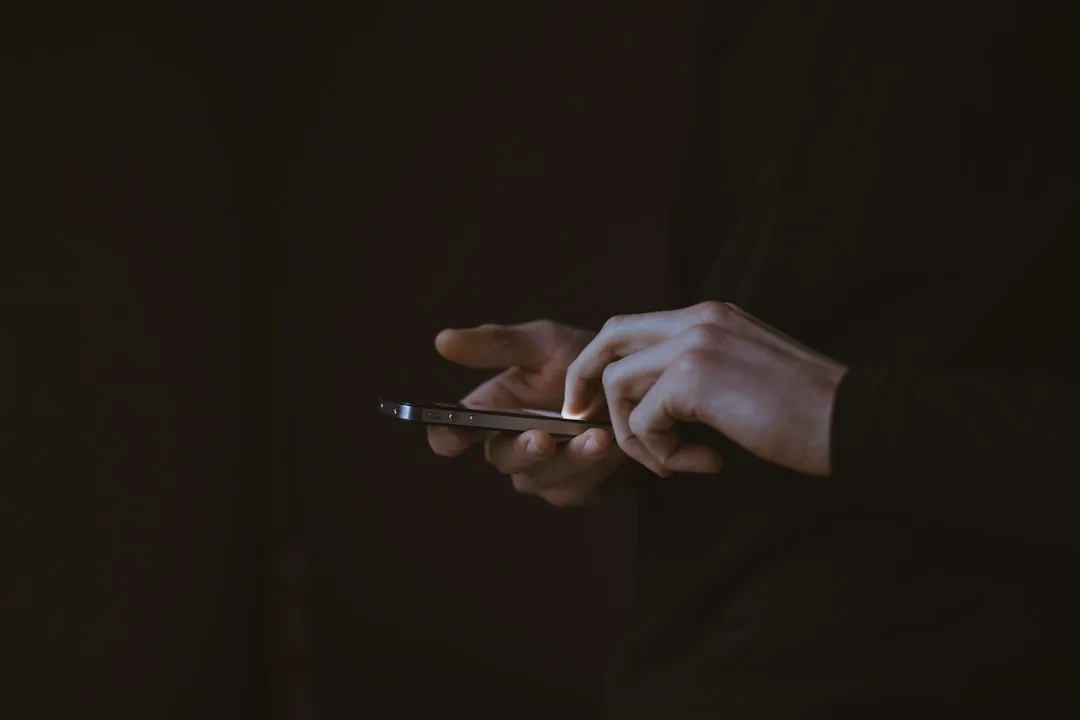Manos usando un móvil en la oscuridad, caso de tráfico de drogas por WhatsApp defendido por Barcelona Penal